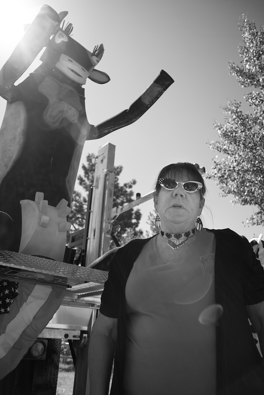 Black and White image of woman standing by parade float of cow